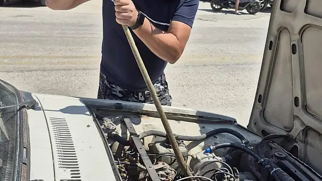 Otomobilin motoruna giren yılanı sopayla çıkardı